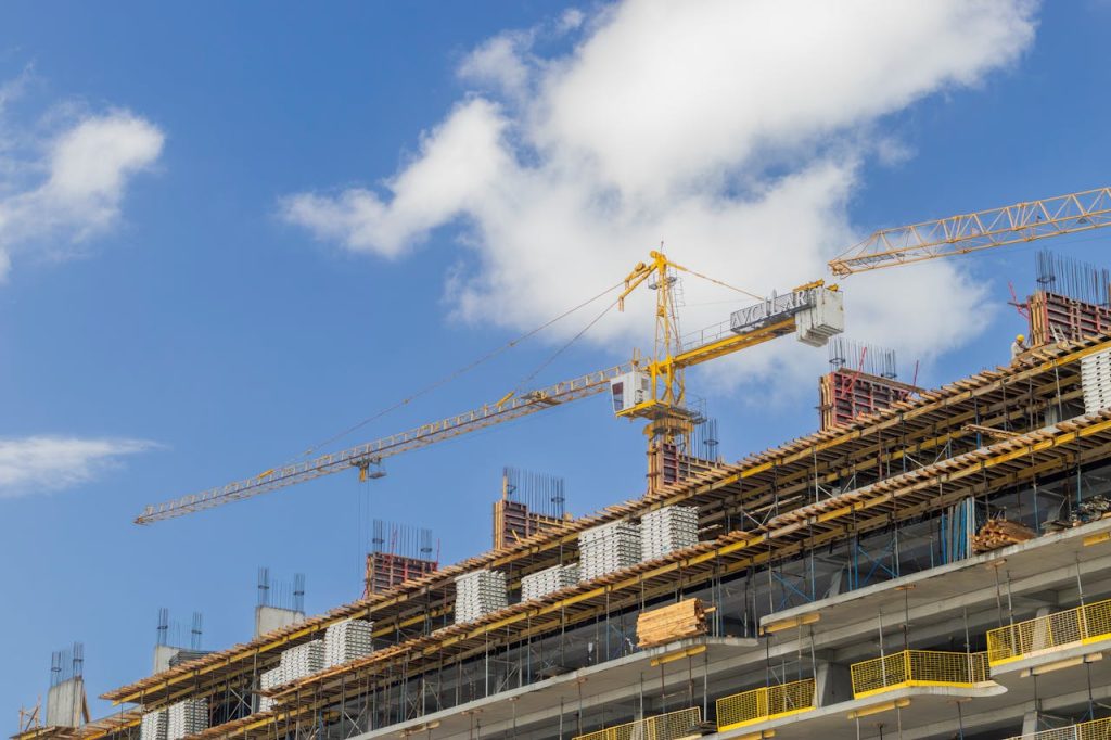 Accueil A modern construction site with cranes against a clear blue sky, showcasing urban development.